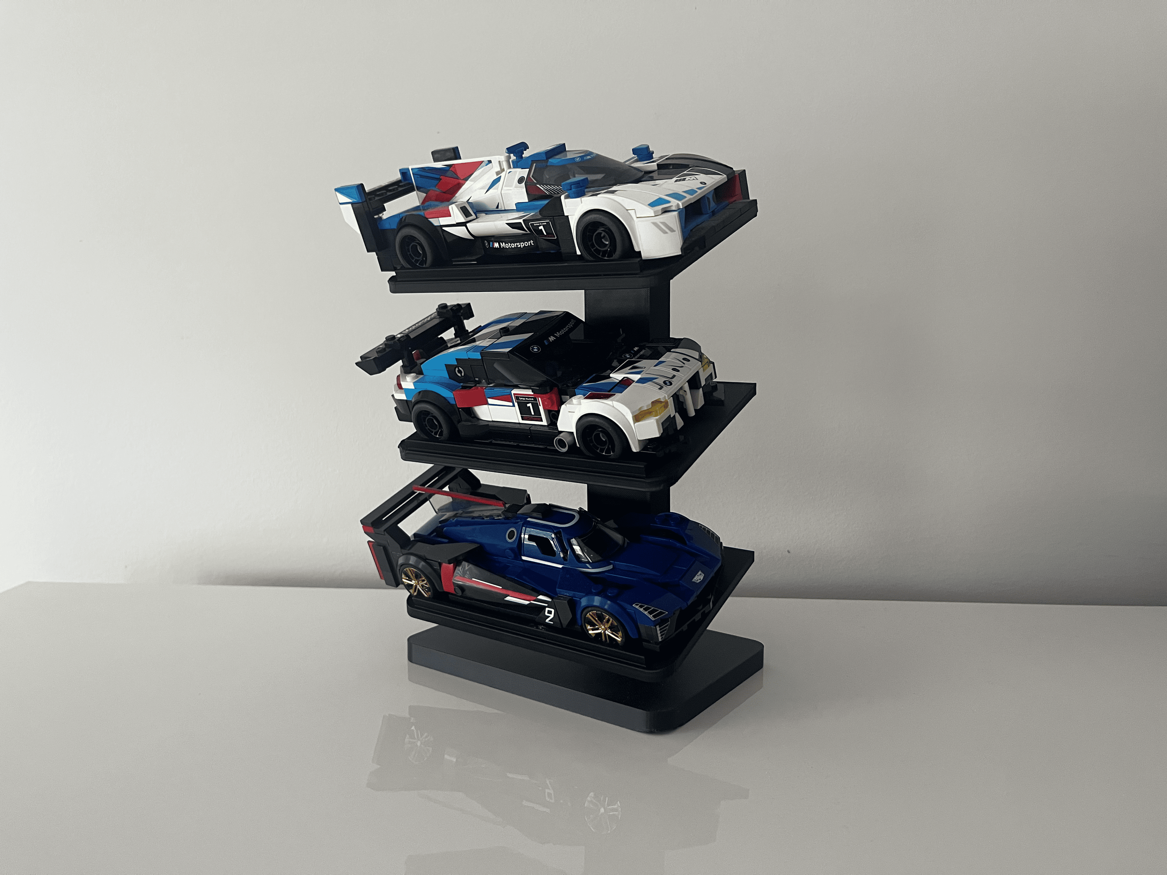 Black three-tier display holding three brick-built race cars