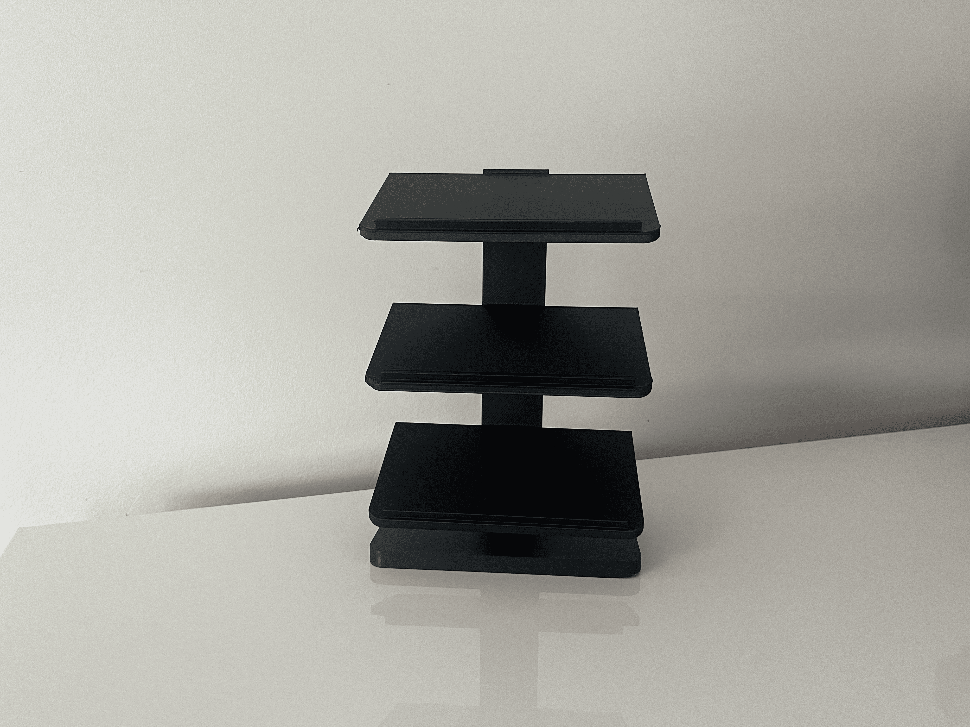 Black three-tier display holding three brick-built race cars